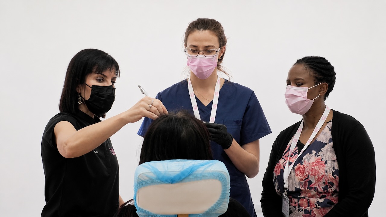 Supervised cosmetic injectables refresher training with practitioners and a live patient