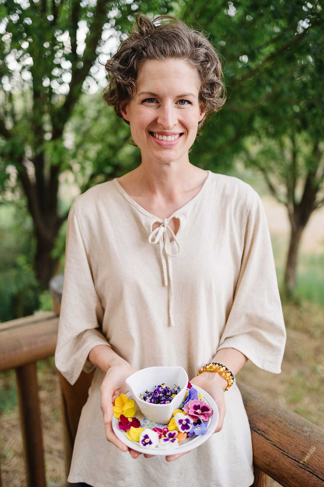 tall slim caucasian woman with short curly hair holding a plate of edible flowers