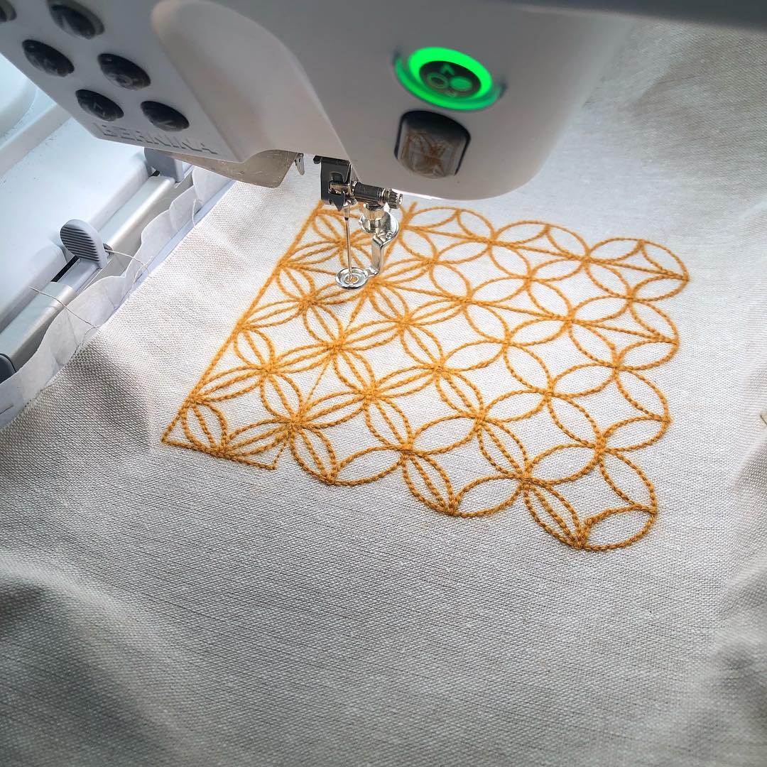 beginner machine embroidery help bernina machine a BERNINA embroidery machine with a finished project sitting under it's needle. The project is a sashiko circle design with golden thread.